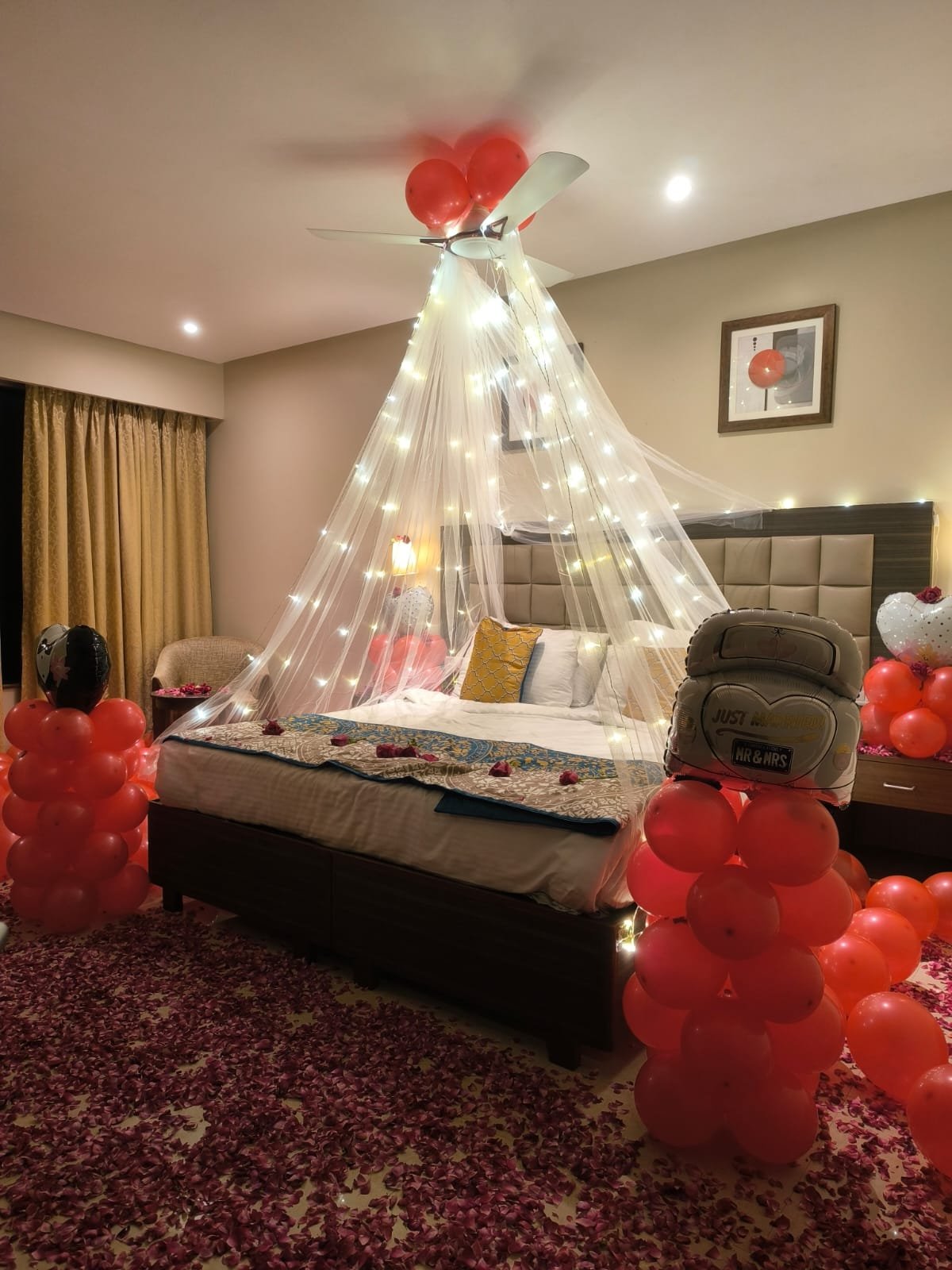 Just Married wedding room balloon decoration with net canopy, fairy lights and rose petals by Star Balloon